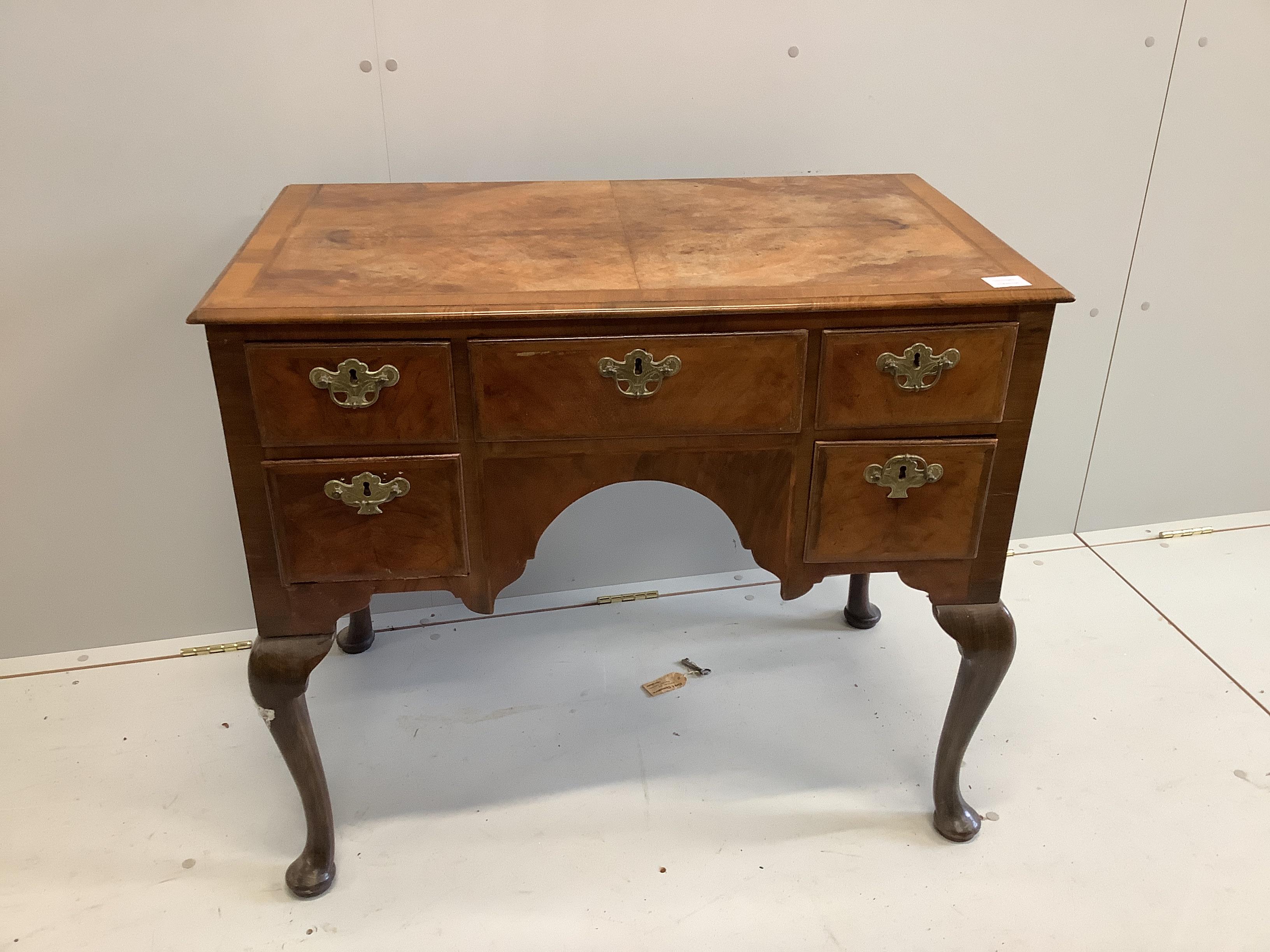 A Queen Anne revival feather banded walnut kneehole dressing table (front leg a/f), width 88cm, depth 50cm, height 75cm